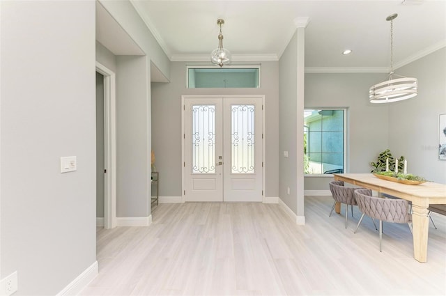 foyer with french doors, an inviting chandelier, ornamental molding, and light hardwood / wood-style flooring