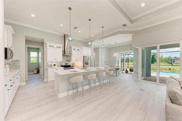 kitchen featuring white cabinetry, backsplash, appliances with stainless steel finishes, a center island with sink, and a wealth of natural light