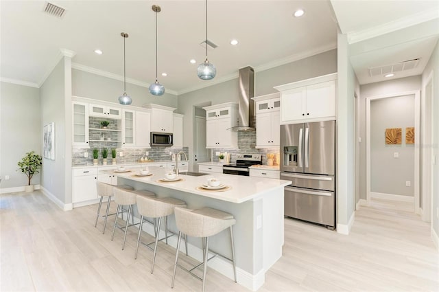 kitchen with a kitchen island with sink, sink, backsplash, stainless steel appliances, and wall chimney exhaust hood