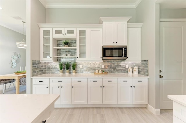 kitchen with white cabinets, crown molding, tasteful backsplash, and light wood-type flooring