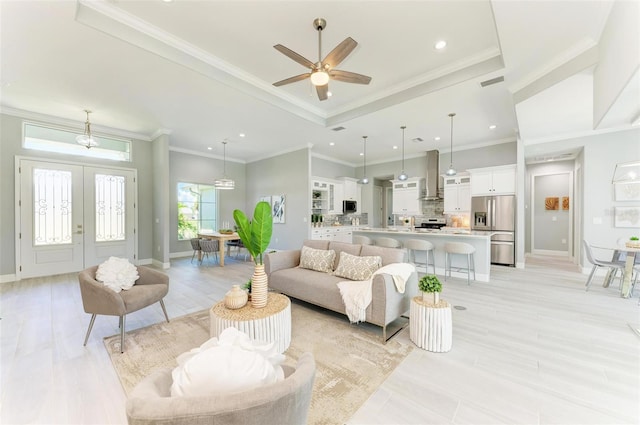 living room with a tray ceiling, ceiling fan, crown molding, and french doors