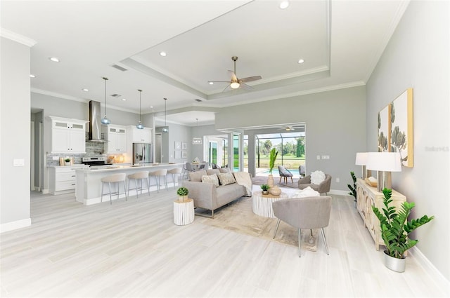 living room with crown molding, ceiling fan, and a tray ceiling