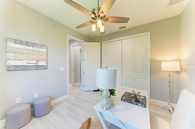 home office with light hardwood / wood-style floors and ceiling fan