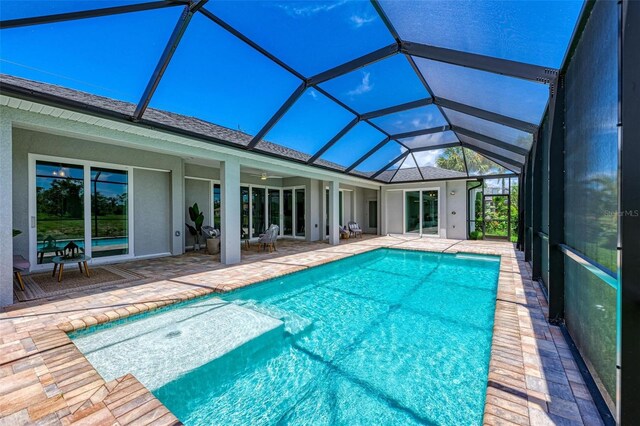 view of swimming pool featuring glass enclosure and a patio