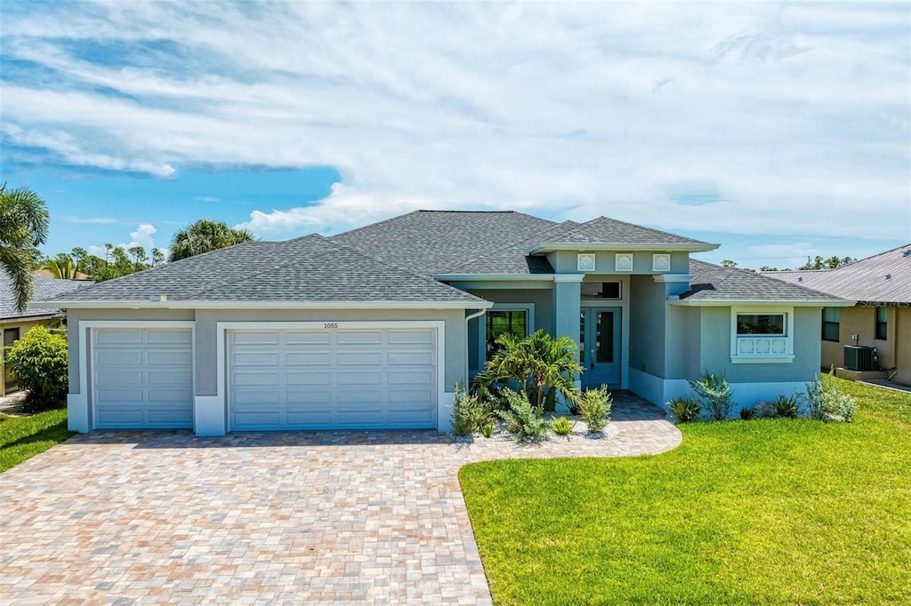 view of front of property featuring a front yard, central air condition unit, and a garage