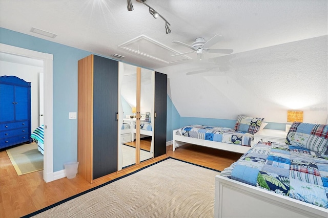 bedroom featuring lofted ceiling, ceiling fan, light hardwood / wood-style flooring, and a textured ceiling