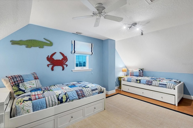 bedroom featuring a textured ceiling, light hardwood / wood-style floors, ceiling fan, and lofted ceiling