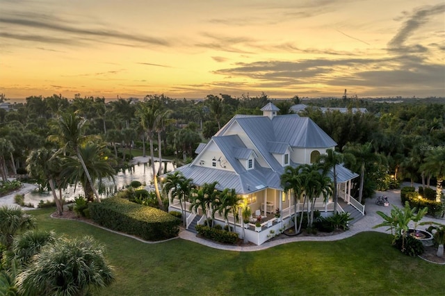 aerial view at dusk featuring a water view