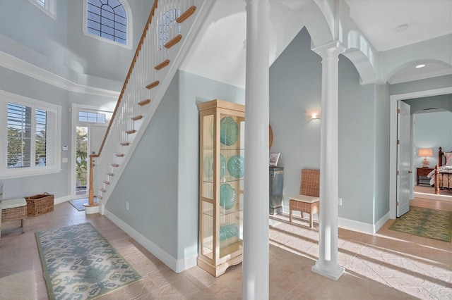 interior space featuring a towering ceiling, decorative columns, and tile patterned floors