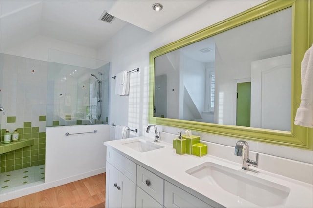 bathroom with hardwood / wood-style flooring, vanity, and a tile shower