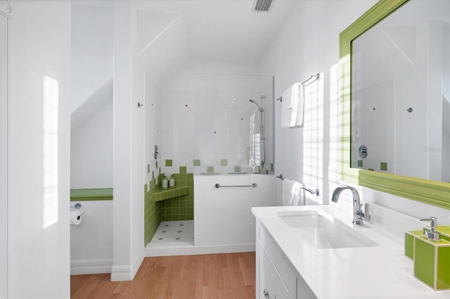 bathroom featuring vanity, wood-type flooring, and tiled shower