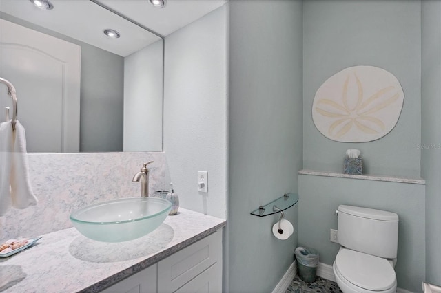 bathroom featuring vanity, toilet, and decorative backsplash