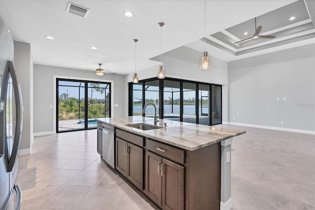 kitchen with ceiling fan, sink, decorative light fixtures, refrigerator, and light stone countertops