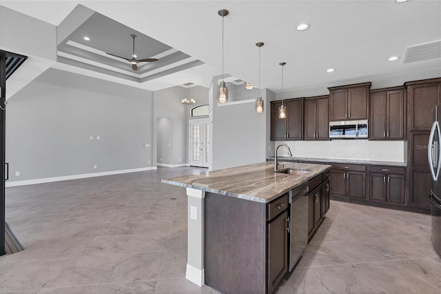 kitchen with stainless steel appliances, tasteful backsplash, light stone counters, sink, and pendant lighting