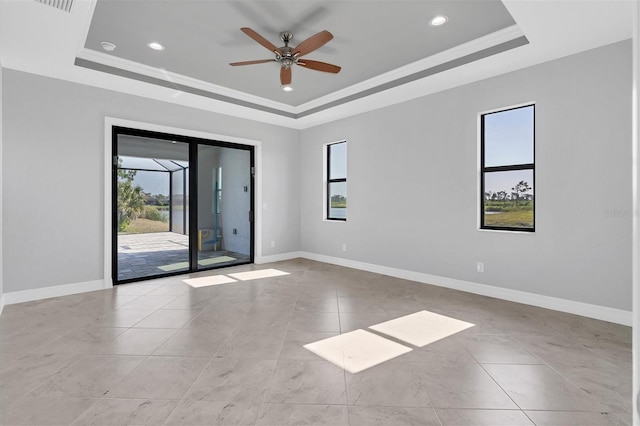 spare room featuring ceiling fan, light tile floors, and a tray ceiling