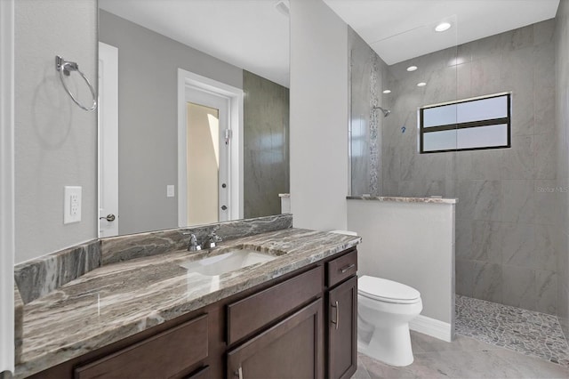 bathroom with tiled shower, toilet, tile floors, and vanity