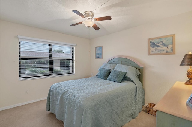 bedroom featuring ceiling fan, light colored carpet, and a textured ceiling