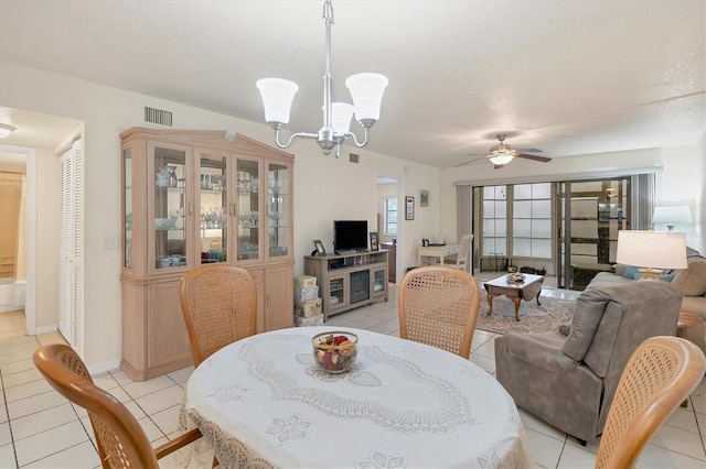 tiled dining space featuring a textured ceiling and ceiling fan with notable chandelier