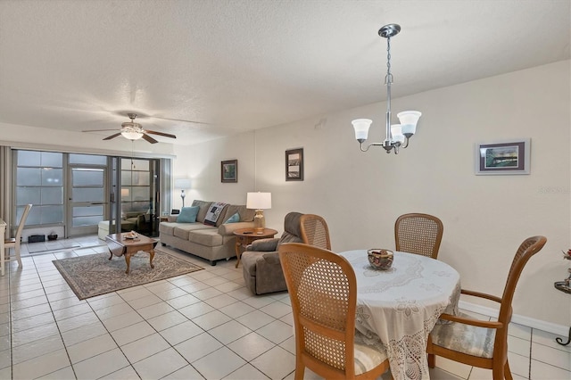 tiled dining room with a textured ceiling and ceiling fan with notable chandelier