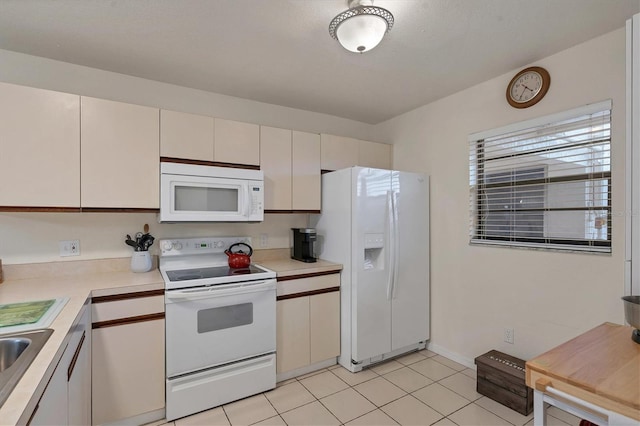 kitchen with white cabinets, light tile patterned flooring, and white appliances