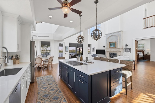 kitchen featuring white cabinetry, dark hardwood / wood-style floors, blue cabinets, an island with sink, and appliances with stainless steel finishes