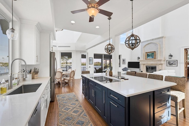 kitchen with sink, dark hardwood / wood-style flooring, blue cabinets, a kitchen island with sink, and white cabinets