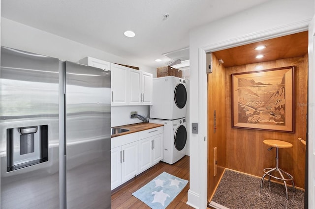 clothes washing area with cabinets, stacked washer / dryer, and dark wood-type flooring