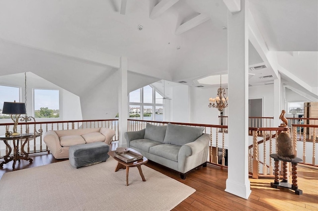 living room featuring a wealth of natural light, high vaulted ceiling, a notable chandelier, and hardwood / wood-style flooring