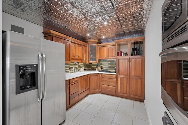 kitchen featuring decorative backsplash, sink, light tile patterned floors, and stainless steel appliances