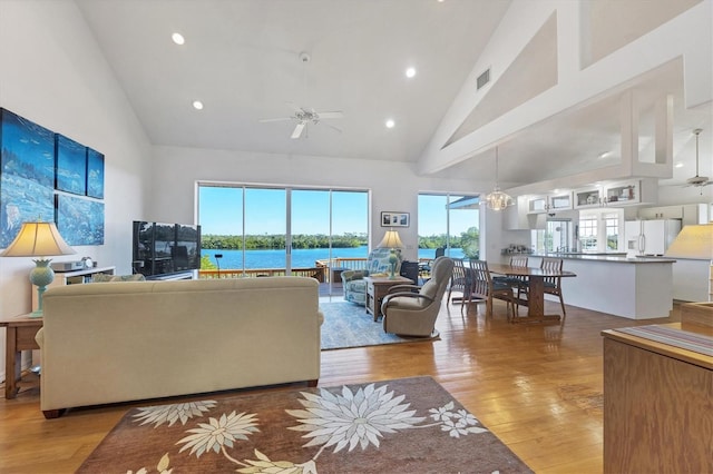 living room featuring ceiling fan with notable chandelier, light hardwood / wood-style floors, and high vaulted ceiling