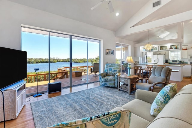 living room featuring ceiling fan with notable chandelier, light hardwood / wood-style floors, high vaulted ceiling, and a healthy amount of sunlight