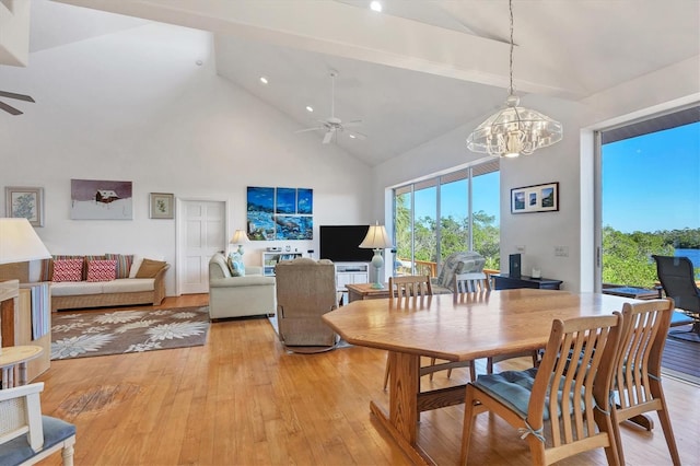 dining room featuring ceiling fan with notable chandelier, light hardwood / wood-style floors, and high vaulted ceiling