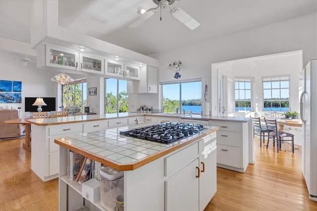 kitchen with white cabinets, ceiling fan with notable chandelier, kitchen peninsula, and a kitchen island