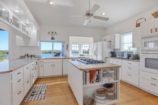 kitchen with white cabinets, kitchen peninsula, white appliances, tile countertops, and ceiling fan