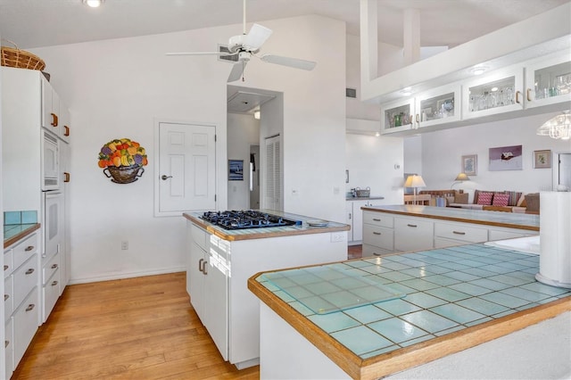 kitchen with ceiling fan, white cabinets, stainless steel gas cooktop, and a kitchen island