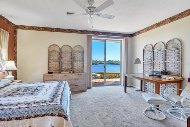 bedroom with multiple windows, a water view, ceiling fan, and access to exterior