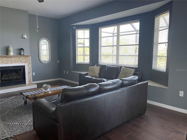 living room with plenty of natural light, dark wood-type flooring, and a tiled fireplace