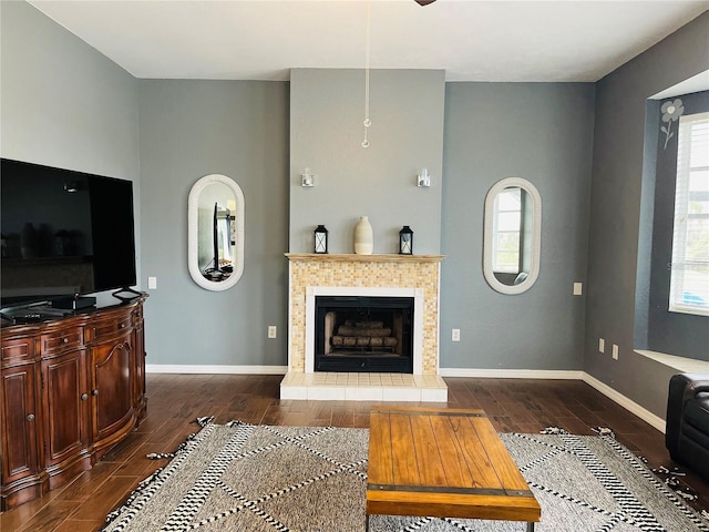 living room featuring a tile fireplace, dark hardwood / wood-style flooring, and a healthy amount of sunlight