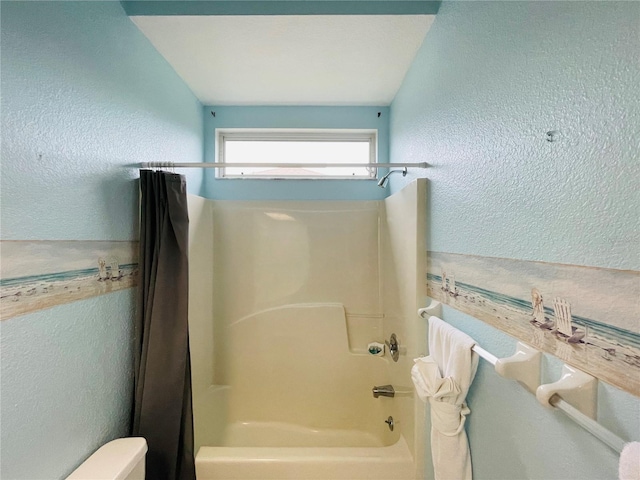 bathroom with shower / bathing tub combination, lofted ceiling, and toilet