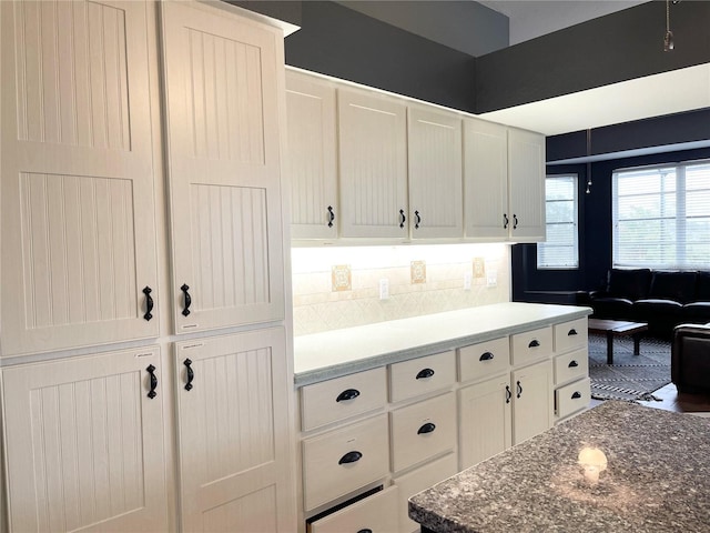 kitchen featuring decorative backsplash, white cabinetry, and dark stone counters