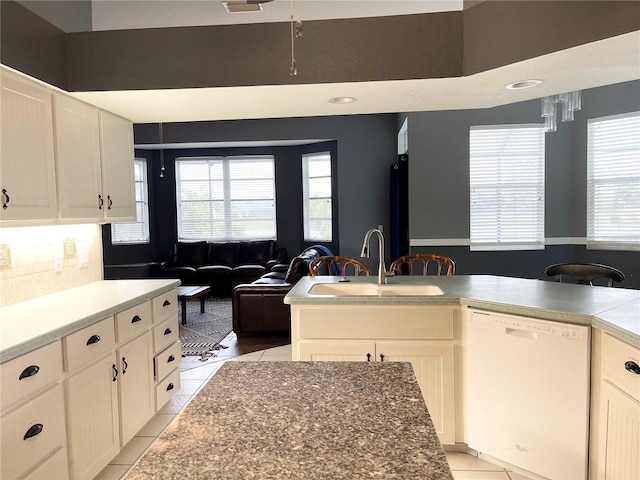 kitchen with white cabinets, dishwasher, light tile patterned floors, and sink