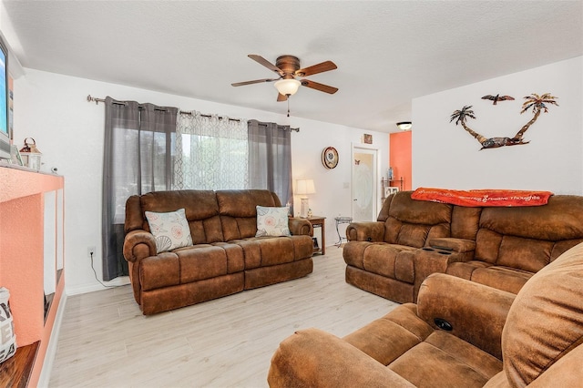 living room featuring ceiling fan, a textured ceiling, and light wood-type flooring