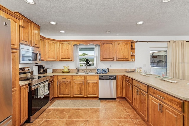 kitchen featuring appliances with stainless steel finishes, sink, light tile patterned floors, and kitchen peninsula