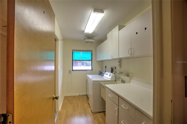 laundry area featuring light hardwood / wood-style floors, cabinets, a textured ceiling, and washing machine and clothes dryer