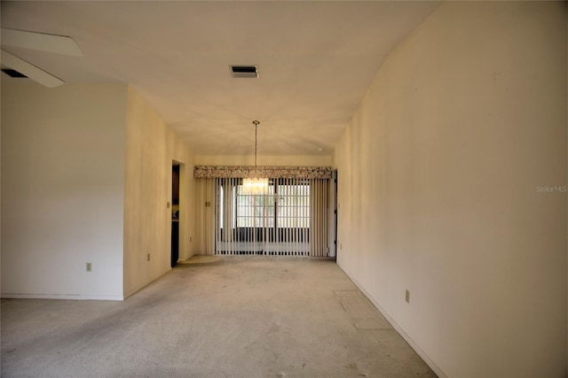 empty room featuring light colored carpet and an inviting chandelier