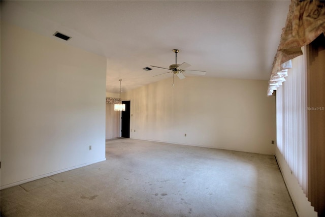 spare room featuring lofted ceiling, plenty of natural light, light colored carpet, and ceiling fan with notable chandelier