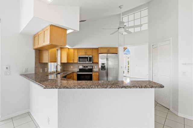 kitchen with high vaulted ceiling, decorative backsplash, ceiling fan, appliances with stainless steel finishes, and kitchen peninsula