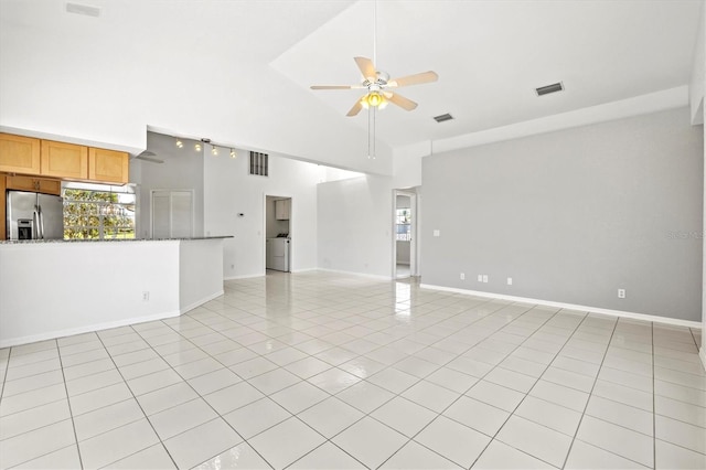 unfurnished living room featuring light tile patterned floors, washer / clothes dryer, high vaulted ceiling, and ceiling fan