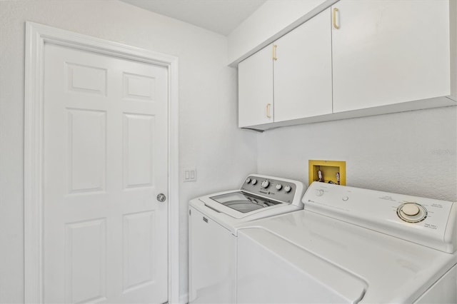 clothes washing area featuring washer and clothes dryer and cabinets