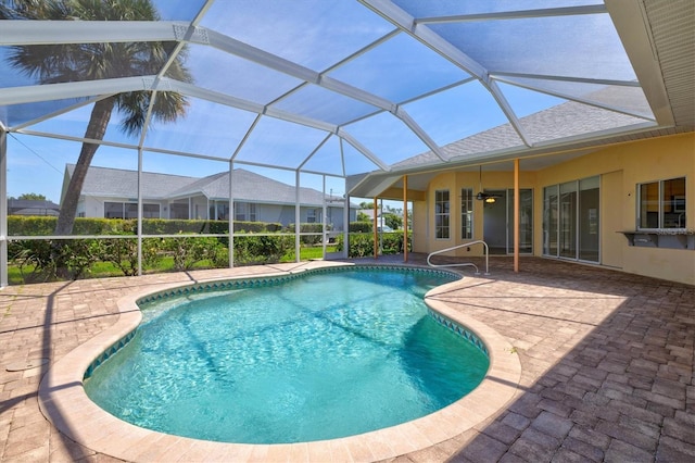 view of swimming pool with glass enclosure, ceiling fan, and a patio area